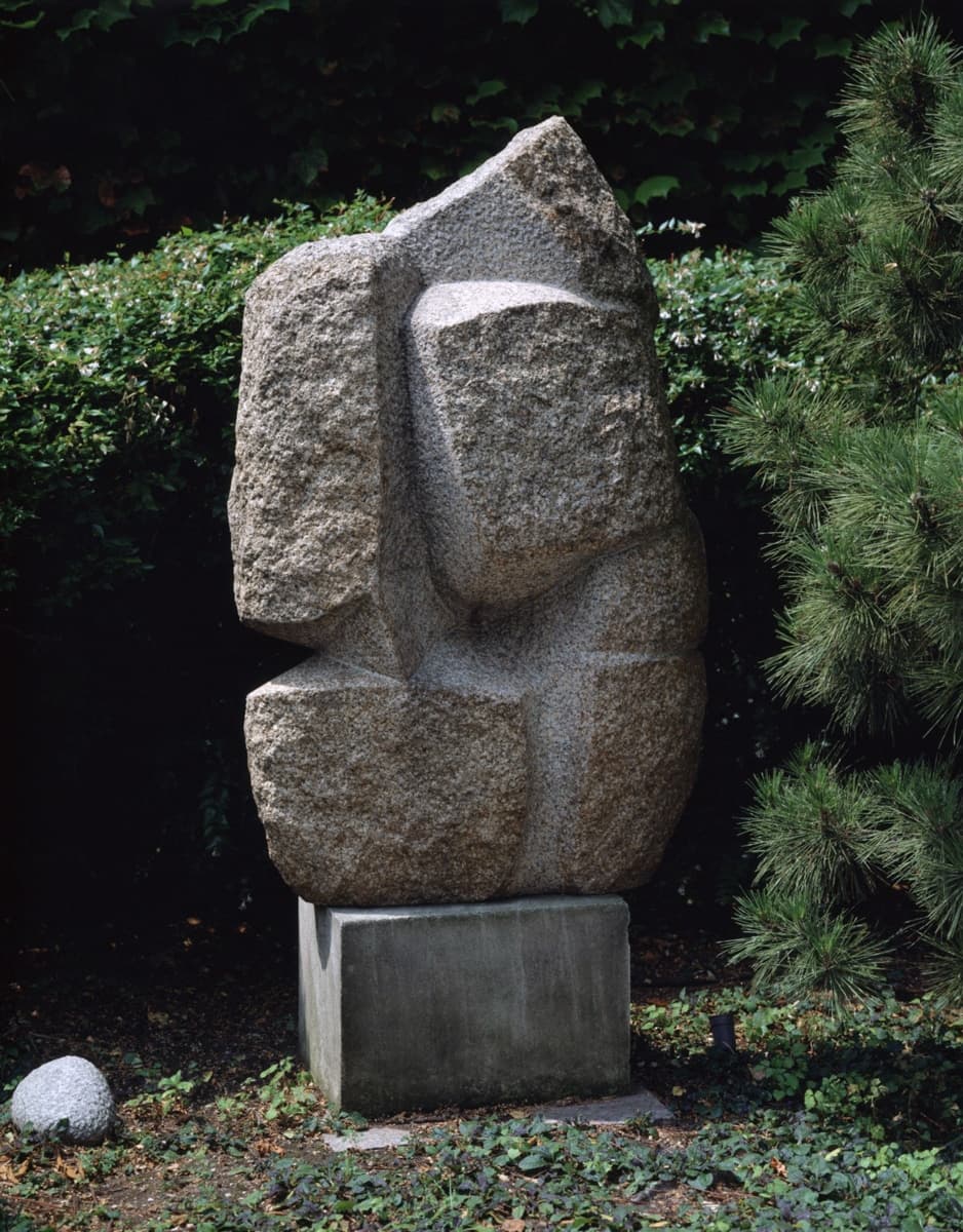A large, angular stone sculpture that mimics the flowing, graceful movements of a dancer. The textured surface evokes the form of a human figure, but the abstract lines and geometric shapes suggest a more modern, interpretive representation of dance and movement.