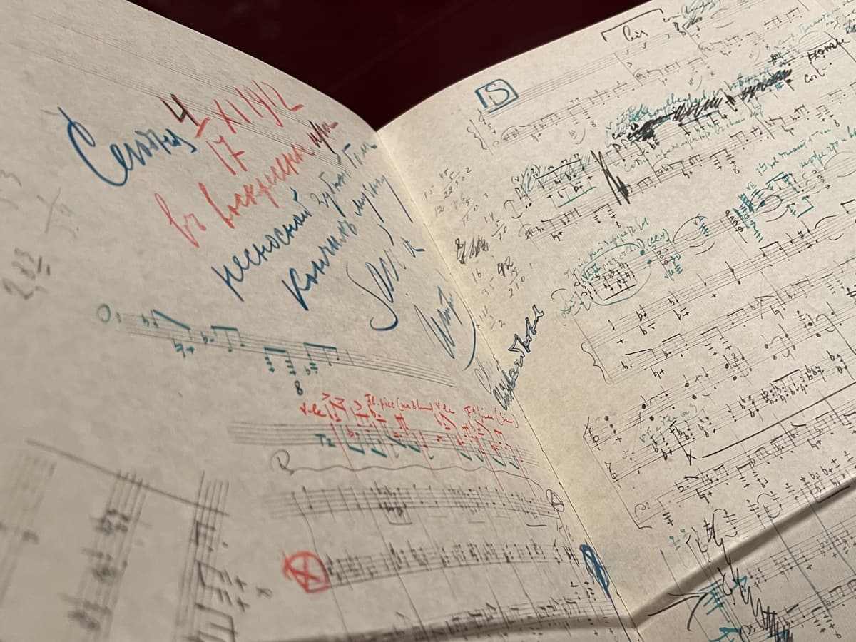 A close-up of a sheet music page covered with extensive handwritten notes and edits in multiple colors of ink, including blue, red, and black. The annotations appear to make corrections, suggestions, and additions to the original musical composition. The colorful handwriting contrasts with the neatly printed musical notes, giving the page an active, creative look as though it is in the midst of revision.