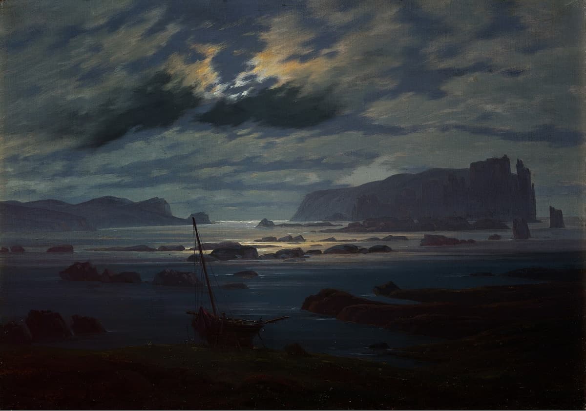 A rugged coastline under a moonlit sky. Waves lap gently under a glowing cloud bank, casting silvery reflections. An abandoned boat lies grounded in the foreground, adding to the stillness.