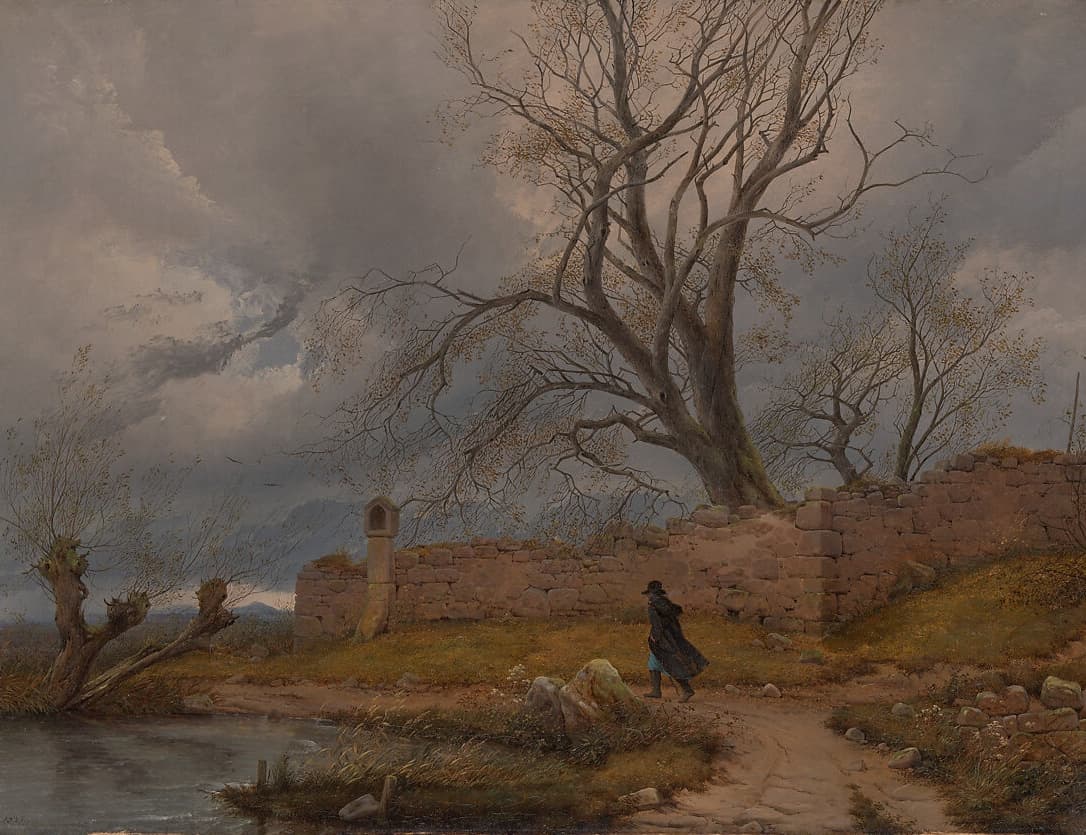 A lone traveler in a dark cloak walks a path beside crumbling stone ruins beneath a massive, leafless tree. The sky is heavy with dark storm clouds, and the landscape exudes a haunting stillness, capturing the sublime tension between man and nature.
