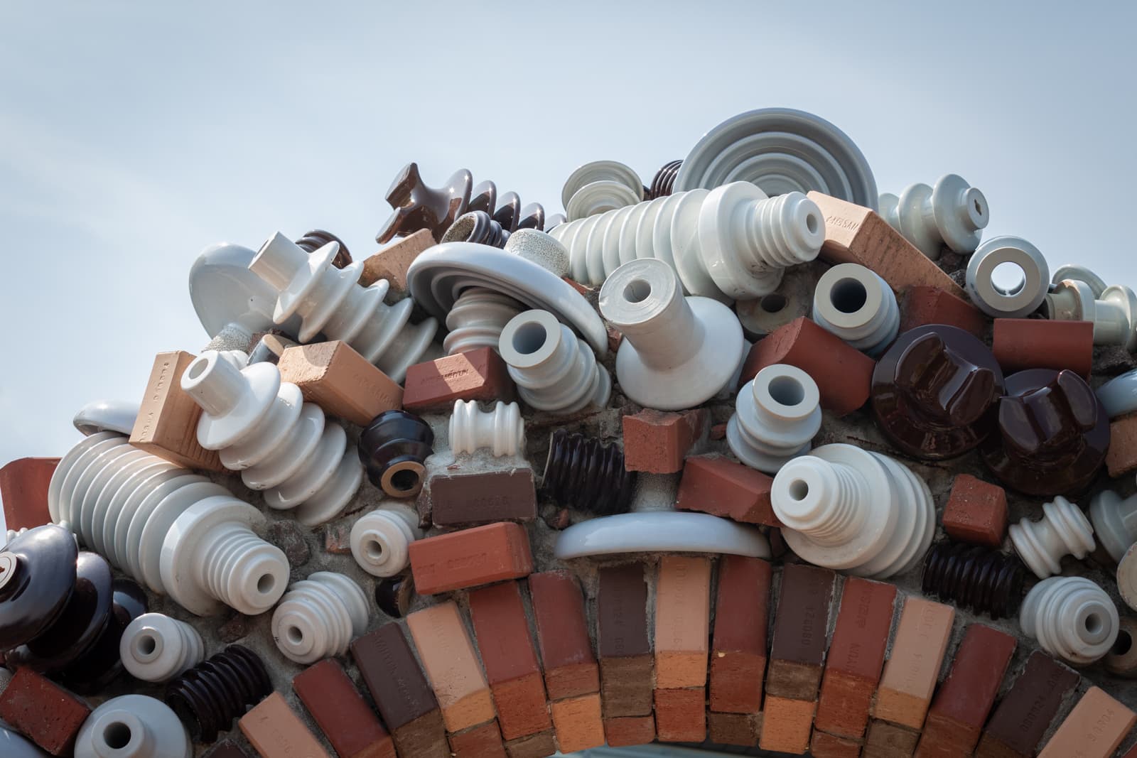 A colorful installation of ceramic insulators and bricks, arranged in a sculptural form, displaying various shapes and sizes.