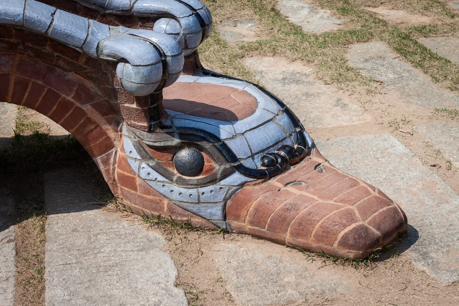 A close-up image of a mosaic dragon sculpture with intricate blue and brown tiles, showcasing the detailed craftsmanship of the dragon's head.