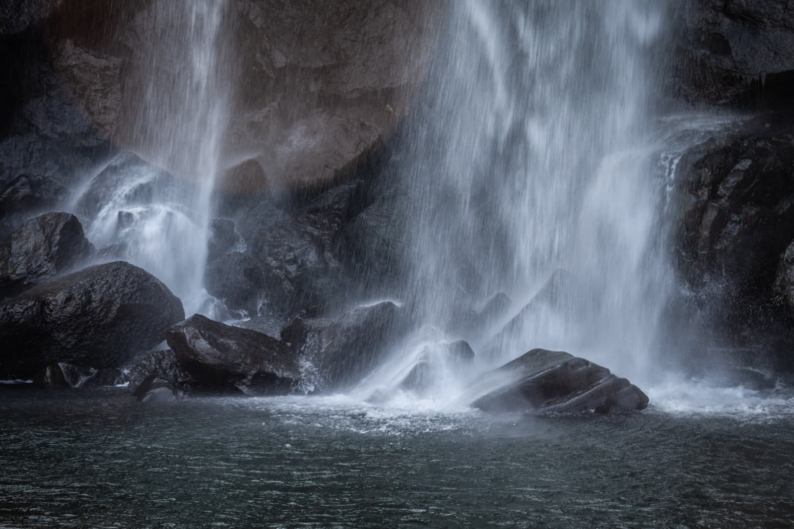 A detailed close-up view of cascading water from a waterfall, with smooth water flowing over dark rocks.