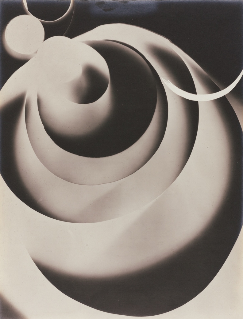 Abstract spiral forms resembling layered ribbons or shells, rendered in smooth gradients of light and shadow, creating a flowing, sculptural composition on a dark background.