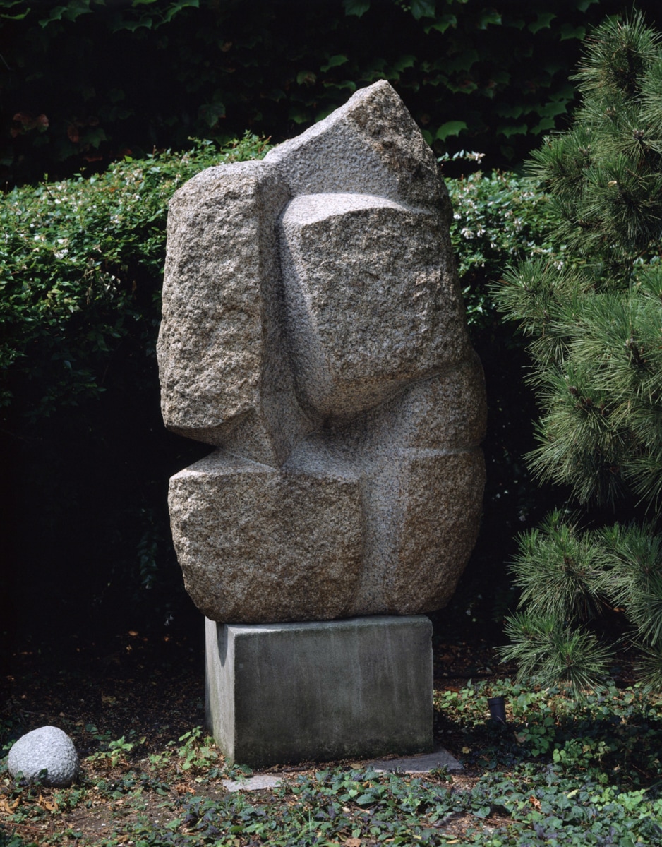 A large, angular stone sculpture that mimics the flowing, graceful movements of a dancer. The textured surface evokes the form of a human figure, but the abstract lines and geometric shapes suggest a more modern, interpretive representation of dance and movement.