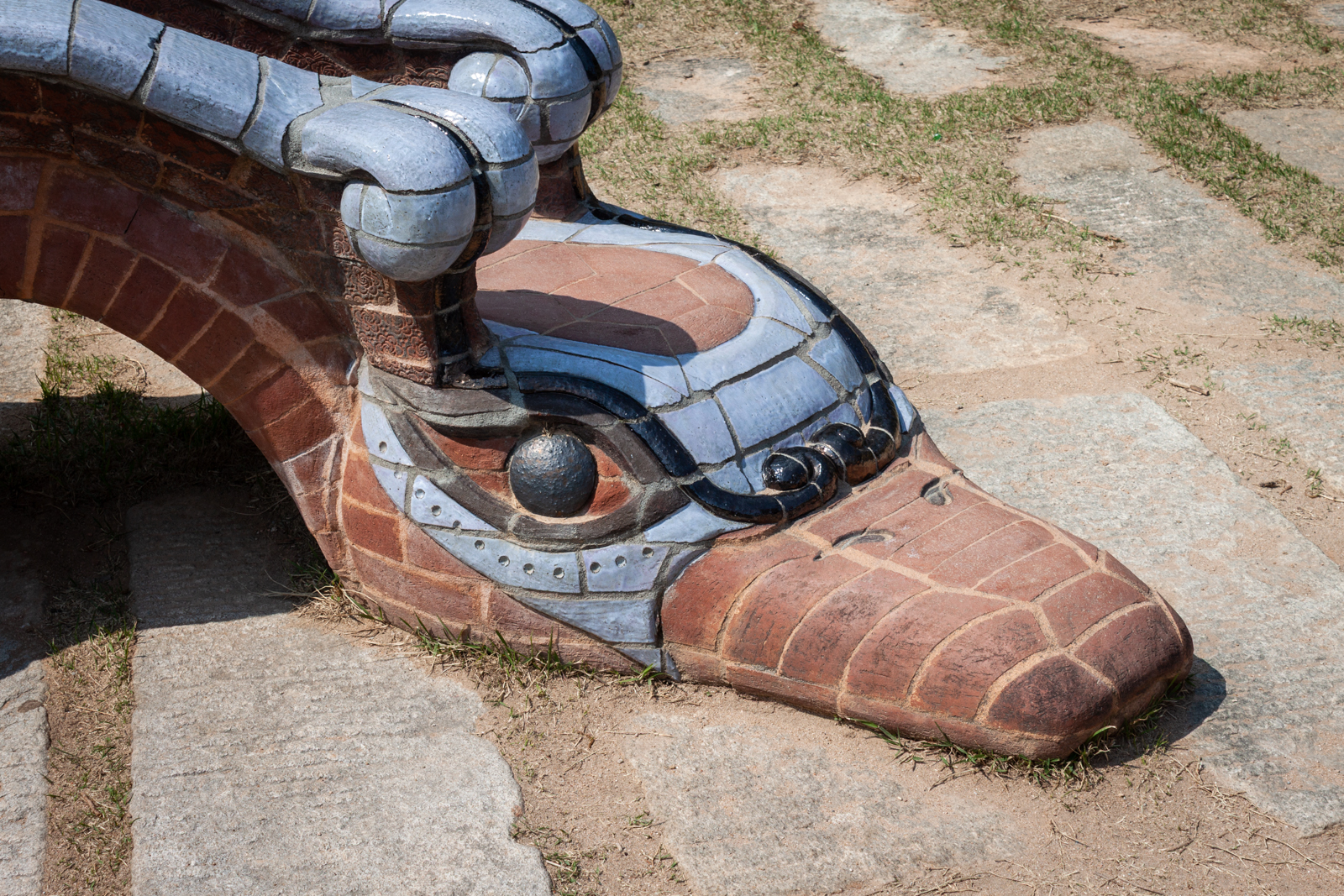 A close-up image of a mosaic dragon sculpture with intricate blue and brown tiles, showcasing the detailed craftsmanship of the dragon's head.
