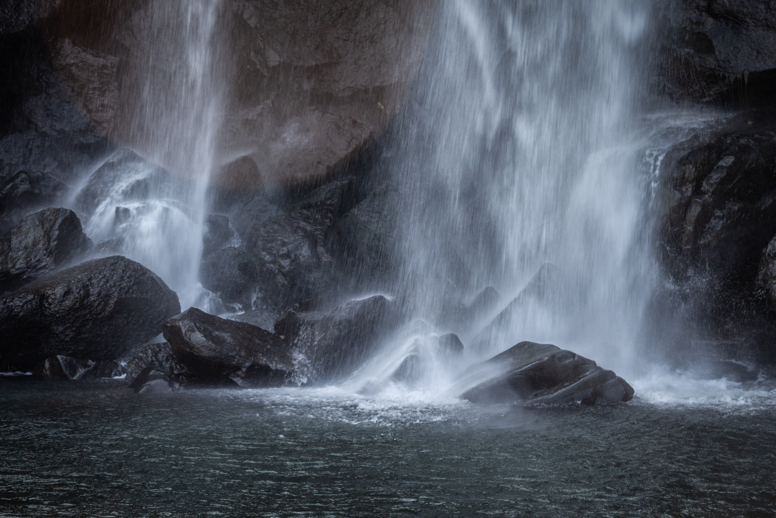 A detailed close-up view of cascading water from a waterfall, with smooth water flowing over dark rocks.